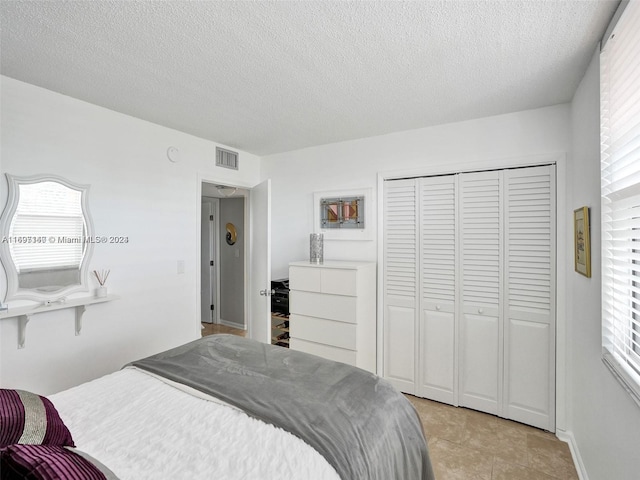 tiled bedroom featuring a closet and a textured ceiling