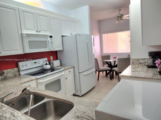 kitchen featuring white appliances, sink, ceiling fan, light tile patterned flooring, and white cabinetry