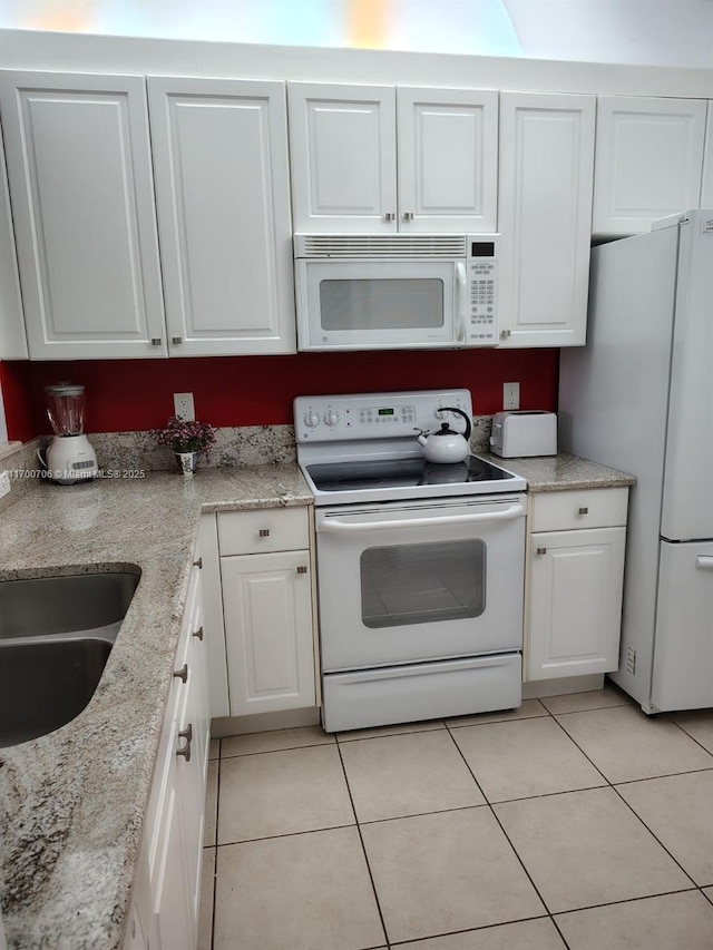 kitchen featuring white cabinets, light tile patterned floors, white appliances, and light stone counters