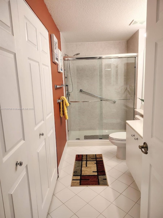 bathroom with tile patterned flooring, toilet, a shower with door, and a textured ceiling