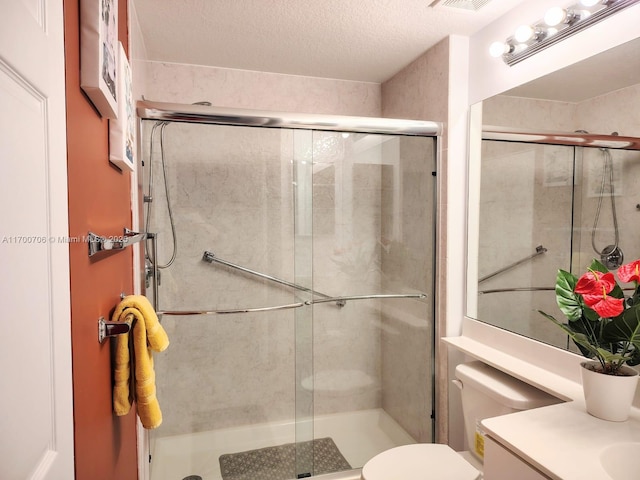 bathroom featuring vanity, a shower with shower door, and toilet