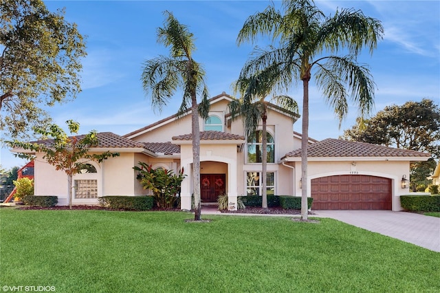 mediterranean / spanish-style home with a garage and a front lawn