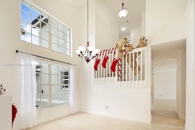 spare room featuring tile patterned floors, a towering ceiling, and an inviting chandelier