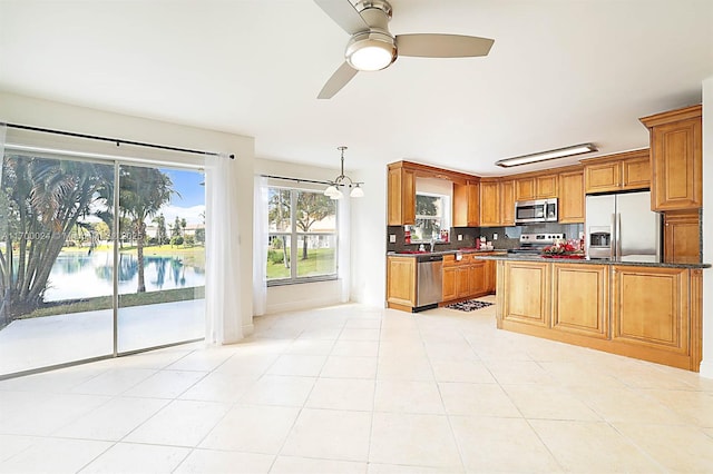 kitchen featuring decorative light fixtures, backsplash, a water view, light tile patterned flooring, and stainless steel appliances