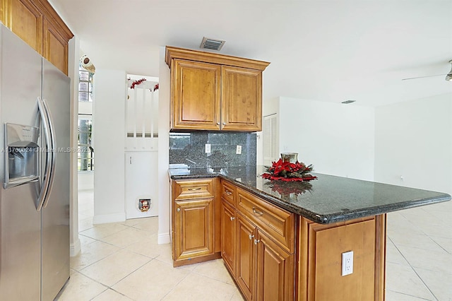 kitchen with stainless steel refrigerator with ice dispenser, ceiling fan, backsplash, dark stone counters, and light tile patterned flooring