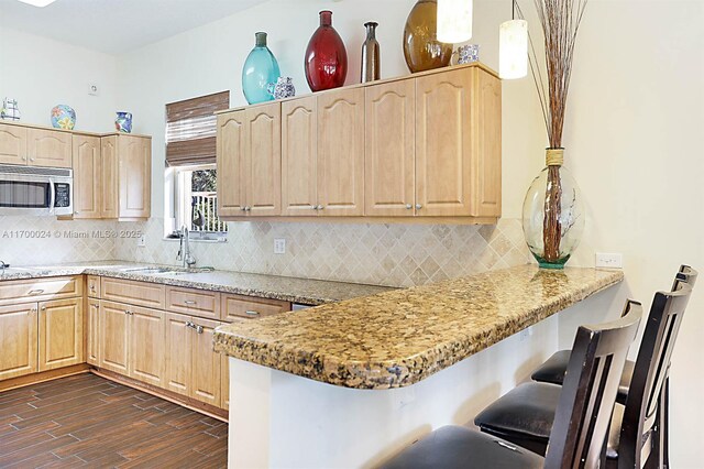 kitchen featuring pendant lighting, light brown cabinetry, sink, backsplash, and kitchen peninsula