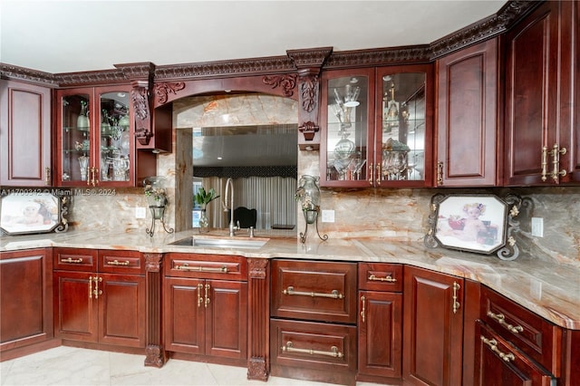 kitchen featuring backsplash, light stone counters, and sink