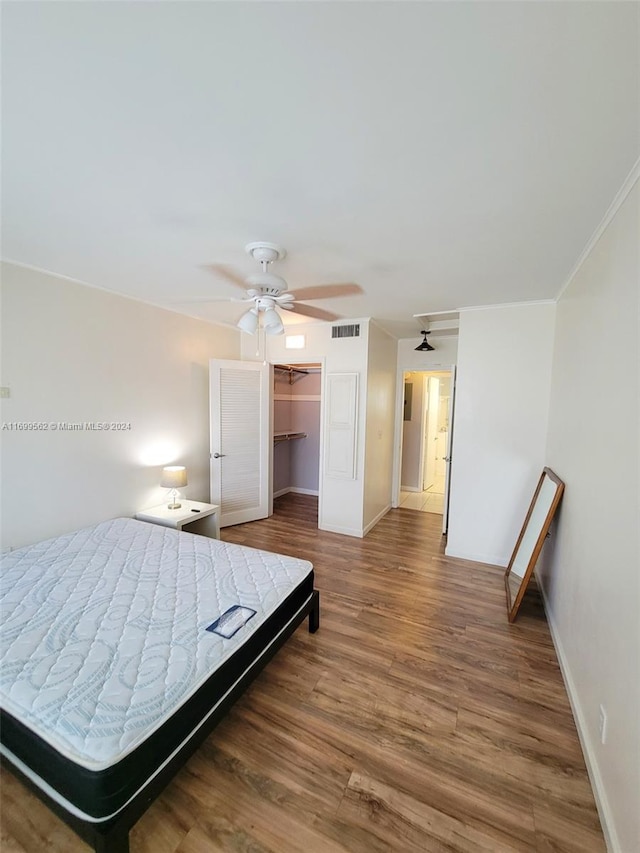 bedroom with ceiling fan, dark hardwood / wood-style floors, a walk in closet, and a closet