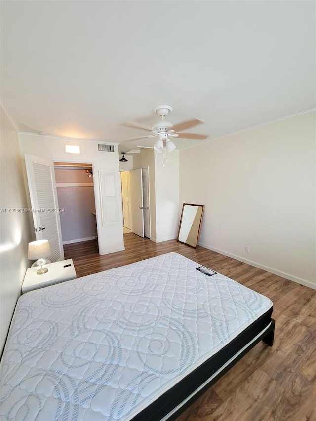 bedroom with a closet, a walk in closet, hardwood / wood-style flooring, and ceiling fan