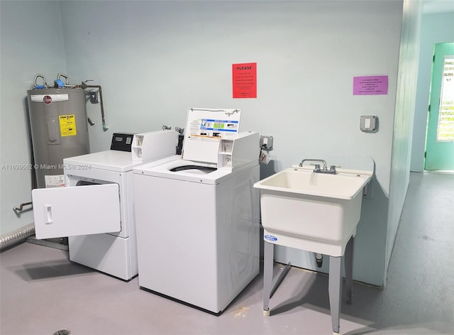 laundry area featuring electric water heater, separate washer and dryer, and sink