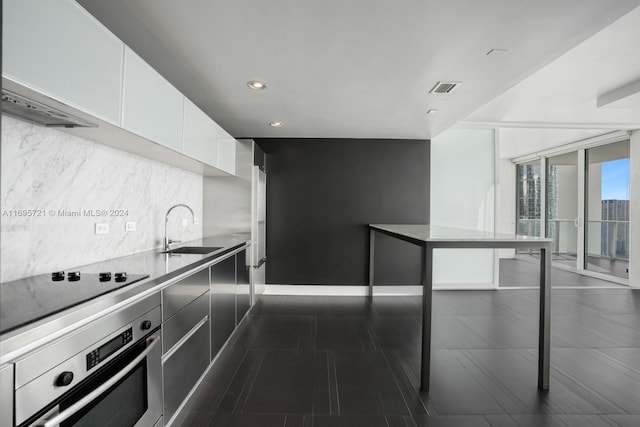 kitchen featuring sink, white cabinets, oven, and black stovetop