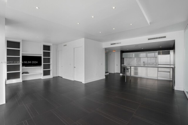 unfurnished living room featuring built in shelves and sink