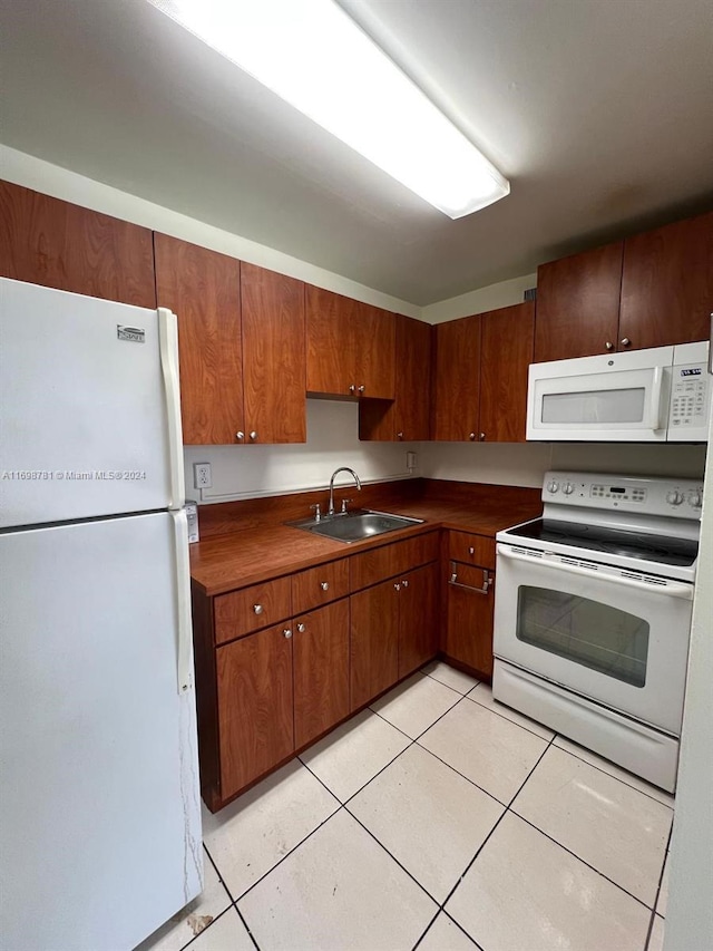 kitchen featuring sink, light tile patterned floors, and white appliances