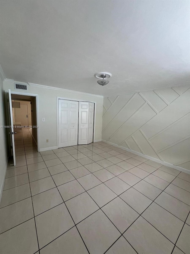 unfurnished bedroom featuring light tile patterned floors, a closet, and crown molding