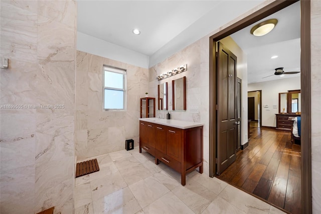 bathroom with hardwood / wood-style flooring, tile walls, vanity, and ceiling fan