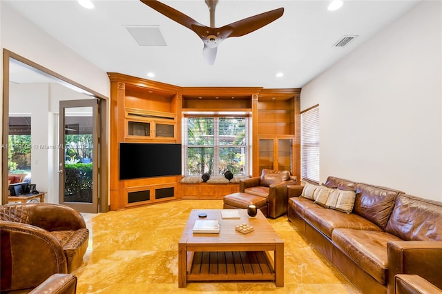 living room with ceiling fan, built in features, and a healthy amount of sunlight