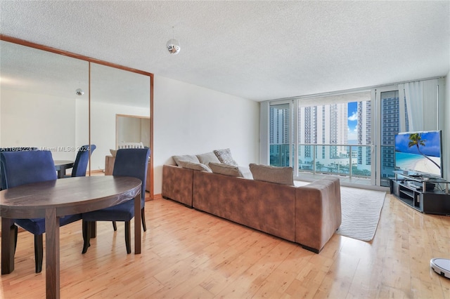 living room featuring a textured ceiling, light hardwood / wood-style floors, and floor to ceiling windows