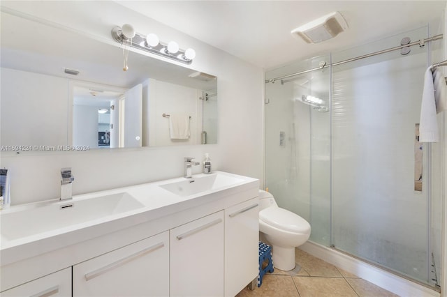 bathroom featuring tile patterned floors, a shower with door, vanity, and toilet