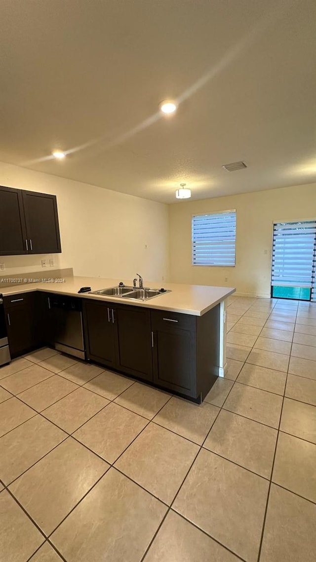 kitchen with appliances with stainless steel finishes, kitchen peninsula, sink, and light tile patterned floors