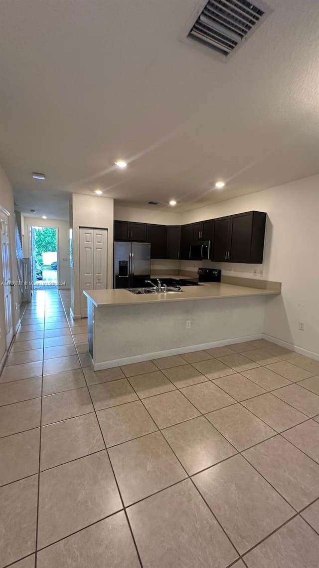 kitchen with kitchen peninsula, sink, stainless steel appliances, and light tile patterned flooring