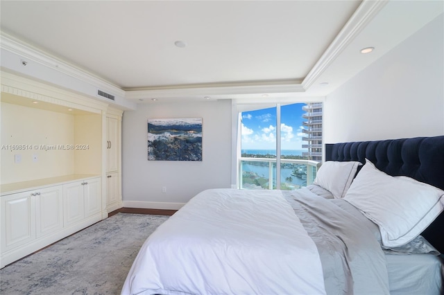 bedroom featuring a water view, crown molding, and light hardwood / wood-style flooring