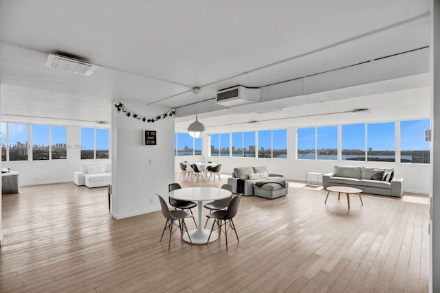 dining space featuring wood-type flooring, a water view, and a healthy amount of sunlight