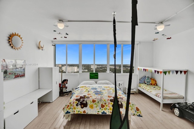 bedroom with light hardwood / wood-style floors, baseboard heating, and ceiling fan