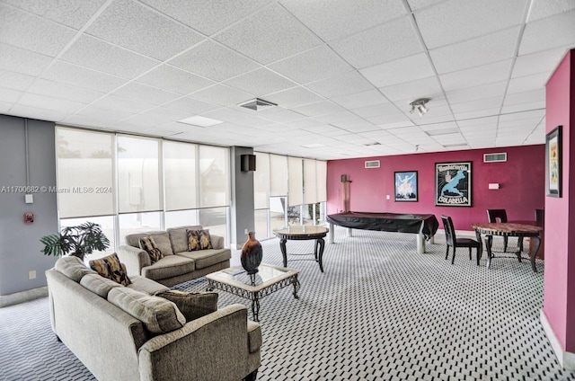 carpeted living room featuring a drop ceiling and a wall of windows