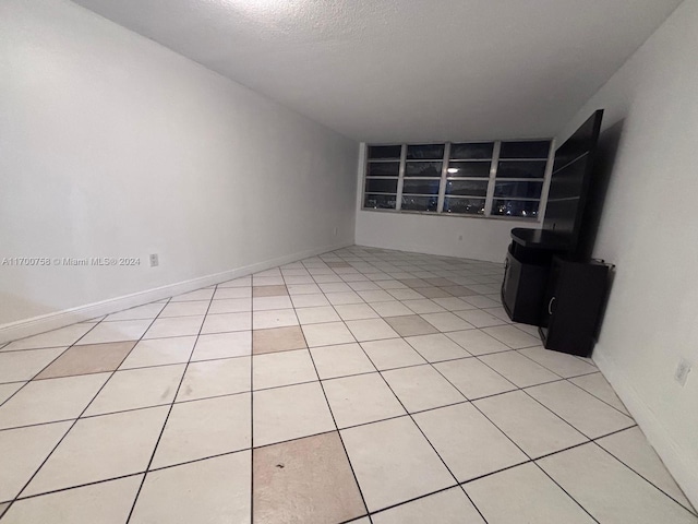 unfurnished living room featuring light tile patterned floors and a textured ceiling