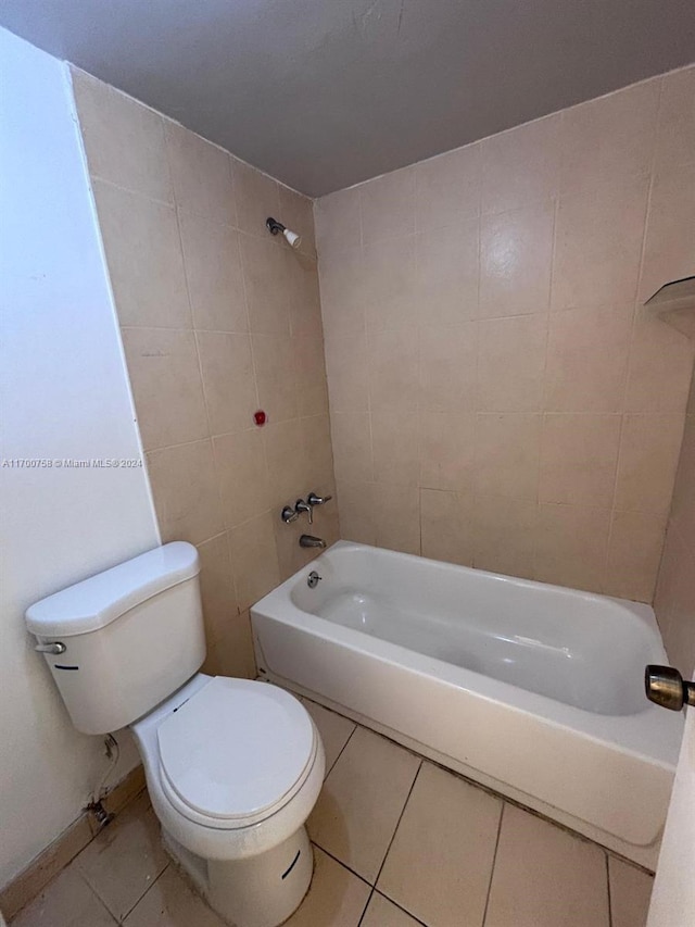 bathroom featuring tile patterned flooring, toilet, and tiled shower / bath