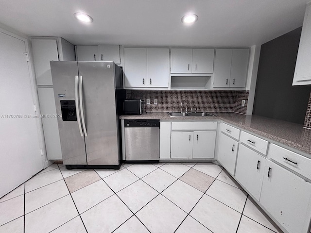 kitchen featuring sink, stainless steel appliances, light tile patterned floors, decorative backsplash, and white cabinets