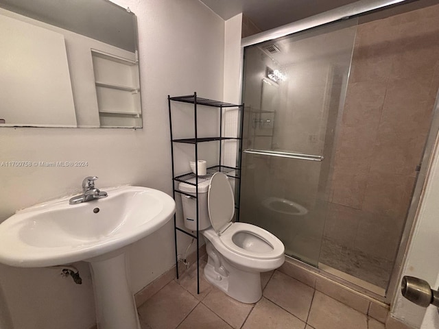 bathroom featuring tile patterned flooring, toilet, and an enclosed shower