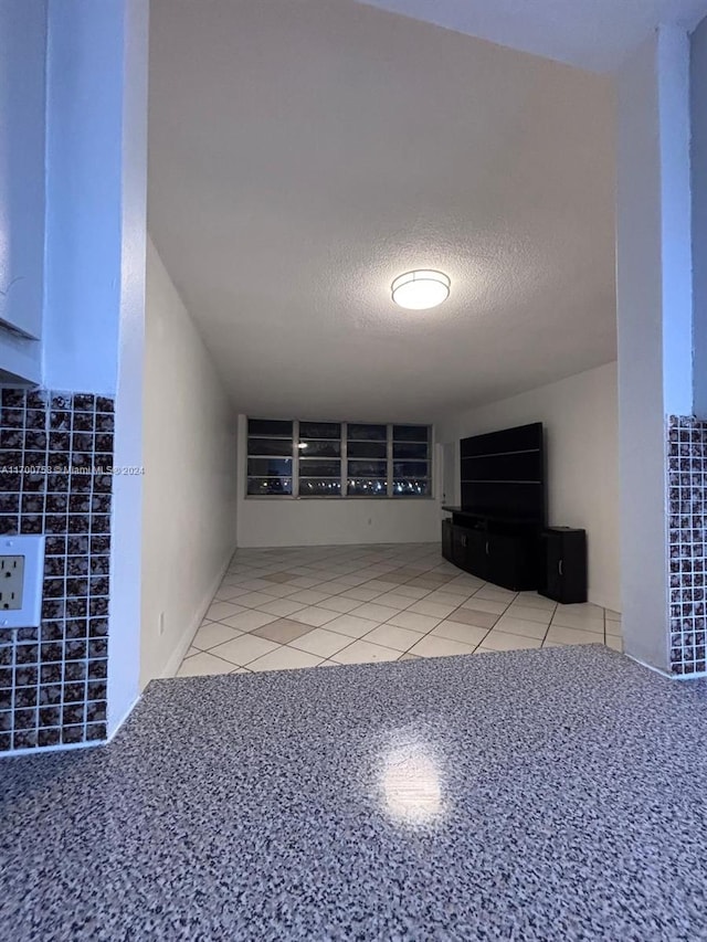 unfurnished living room featuring a textured ceiling and tile patterned floors