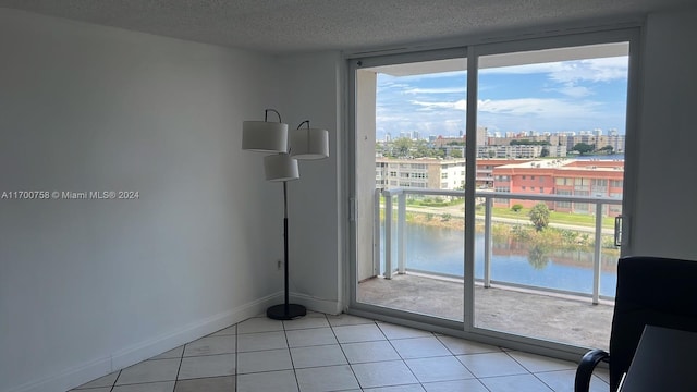 spare room featuring a textured ceiling, a water view, and light tile patterned floors