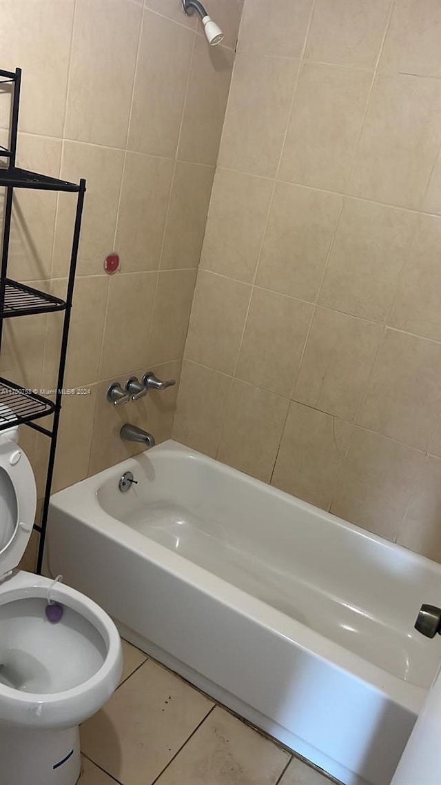 bathroom with tile patterned floors, tiled shower / bath, and toilet