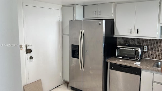 kitchen with decorative backsplash, light tile patterned floors, stainless steel appliances, and white cabinets