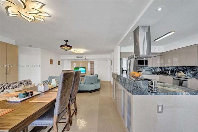 kitchen featuring decorative backsplash, dark stone countertops, light tile patterned floors, appliances with stainless steel finishes, and island exhaust hood