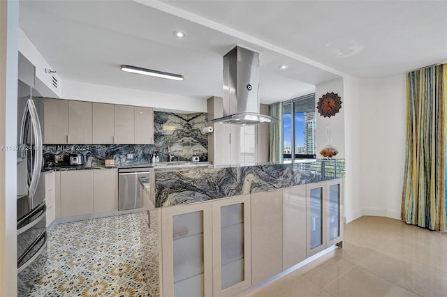 kitchen featuring island exhaust hood, decorative backsplash, stainless steel appliances, dark stone countertops, and gray cabinets