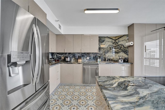 kitchen featuring gray cabinets, dark stone countertops, stainless steel appliances, and tasteful backsplash