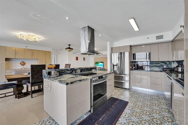 kitchen featuring island exhaust hood, backsplash, stainless steel appliances, and dark stone countertops