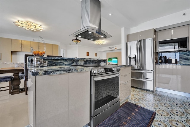 kitchen with island exhaust hood, stainless steel appliances, and dark stone countertops