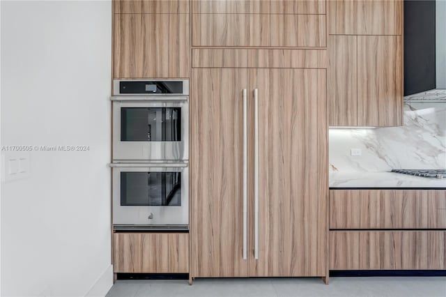 kitchen with decorative backsplash, light stone counters, and double oven