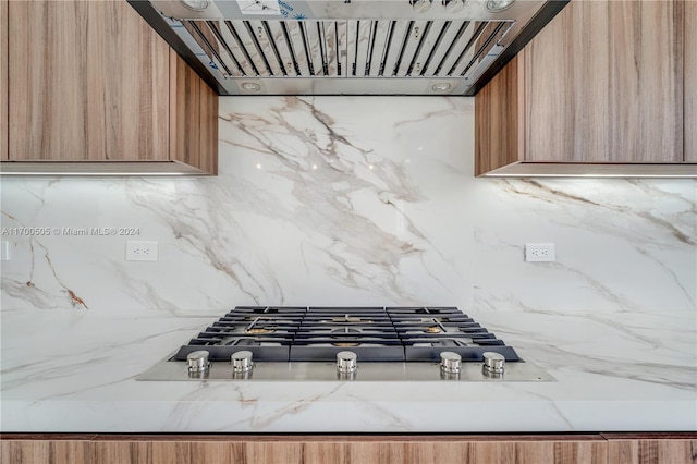 room details featuring ventilation hood, stainless steel gas cooktop, and tasteful backsplash