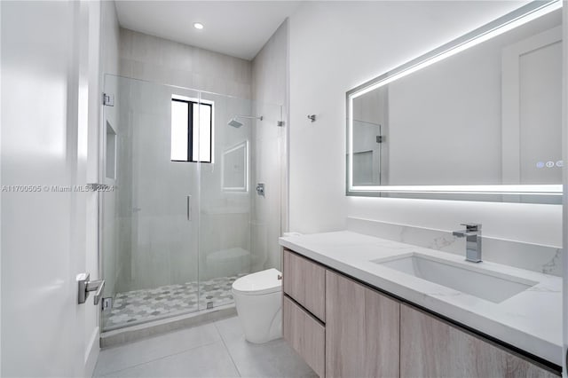 bathroom featuring tile patterned flooring, vanity, toilet, and a shower with door