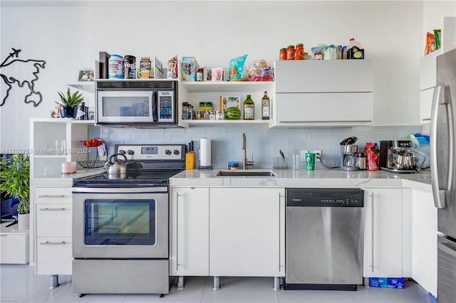 kitchen featuring backsplash, sink, light tile patterned floors, appliances with stainless steel finishes, and white cabinetry