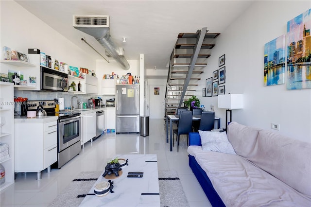 kitchen with white cabinetry, sink, tasteful backsplash, light tile patterned floors, and appliances with stainless steel finishes