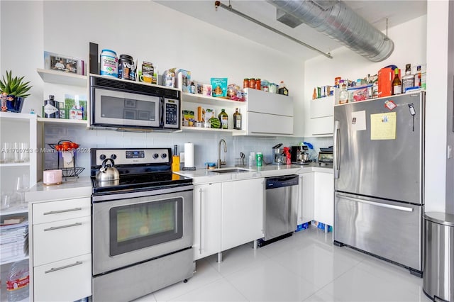 kitchen featuring white cabinetry, sink, tasteful backsplash, light tile patterned flooring, and appliances with stainless steel finishes