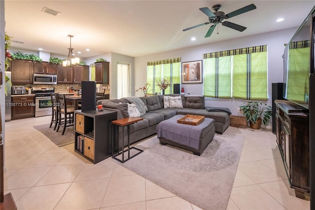 tiled living room with ceiling fan with notable chandelier