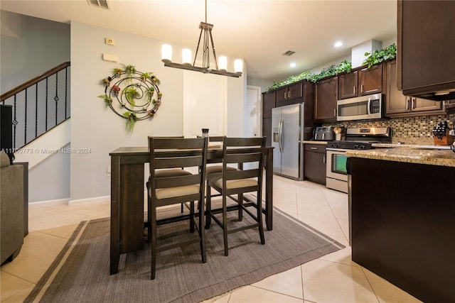 kitchen featuring decorative backsplash, light tile patterned floors, stainless steel appliances, and decorative light fixtures