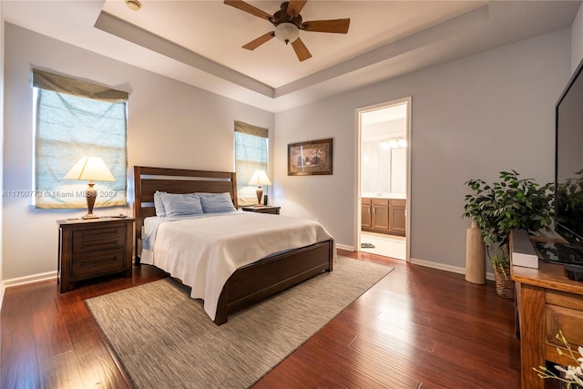 bedroom with a raised ceiling, ceiling fan, dark hardwood / wood-style flooring, and ensuite bathroom